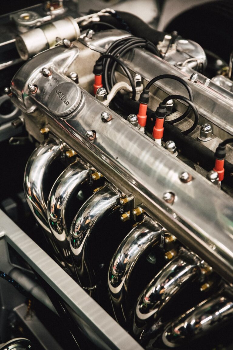 A person examining a diesel engine with the hood open and visible engine components outdoors.
