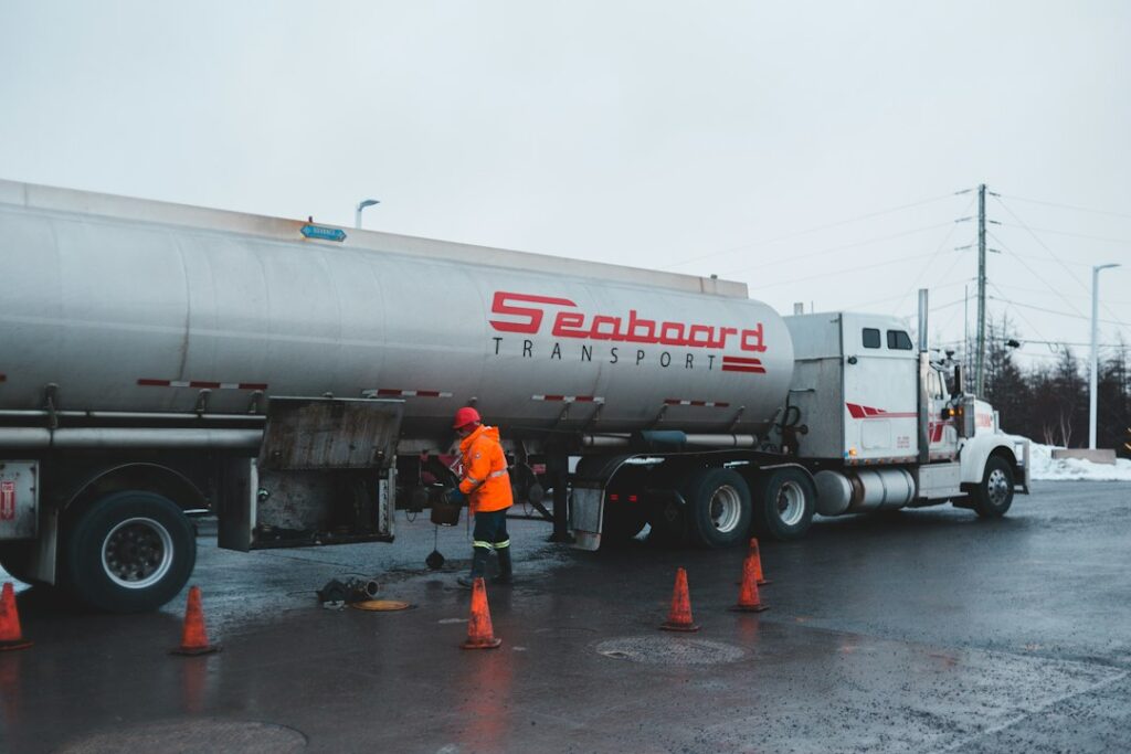 A person checks a diesel engine battery, coolant reservoir, and fuel filter on a cold outdoor morning.