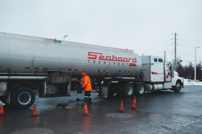 A person checks a diesel engine battery, coolant reservoir, and fuel filter on a cold outdoor morning.